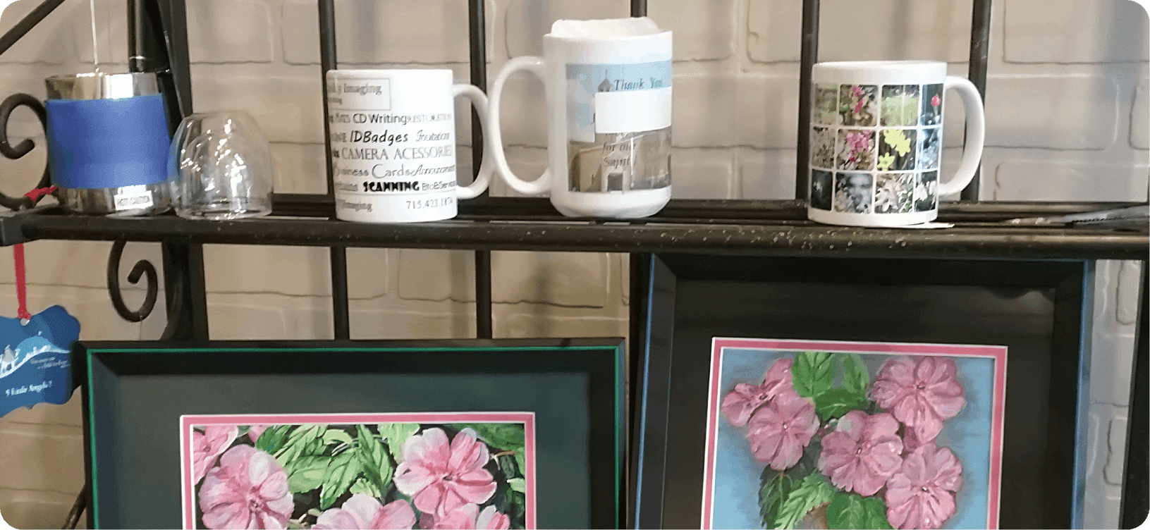 Mugs and floral paintings on display shelf.