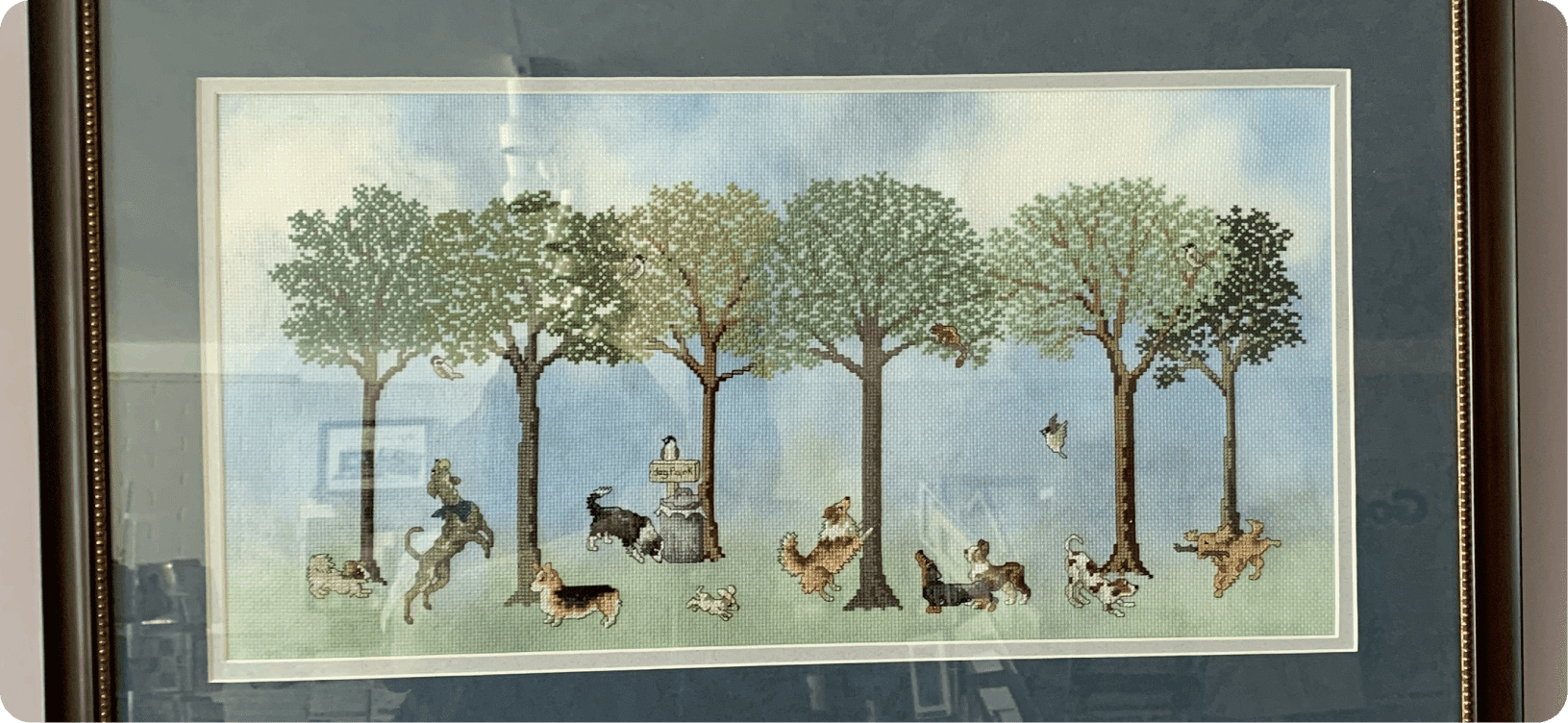 Framed artwork of dogs playing among trees.